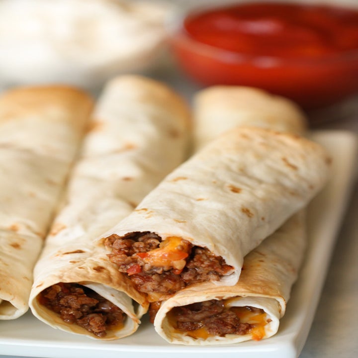 Four taquitos filled with ground beef, cheese, and salsa.