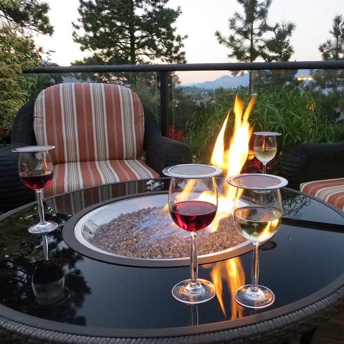 Four wine glasses on an outdoor table with wine guards on top of them
