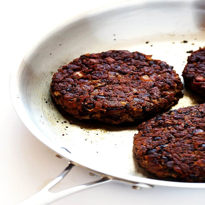 Three black bean patties cooking in a skillet.