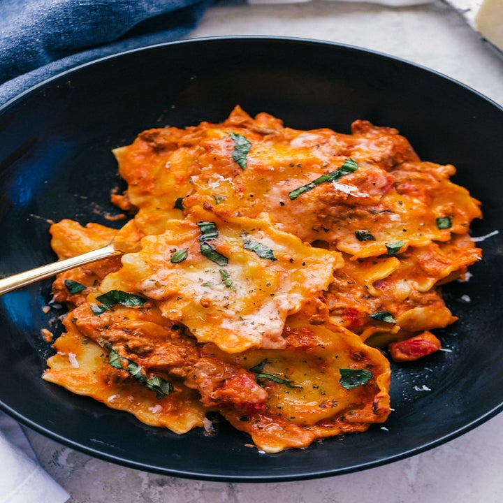 A plate of baked ravioli in tomato sauce.