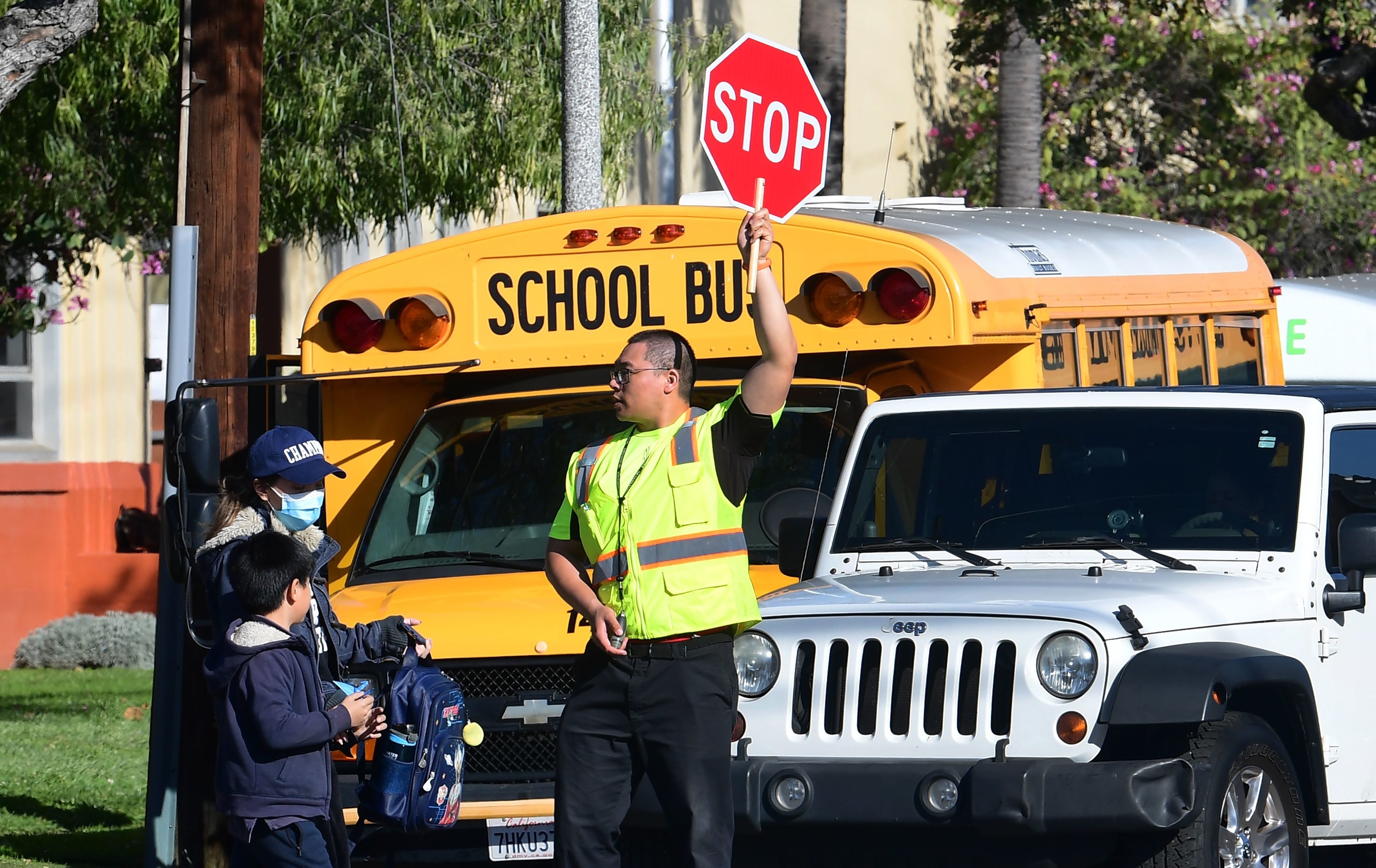 A crossing guard stops traffic in front of a school bus