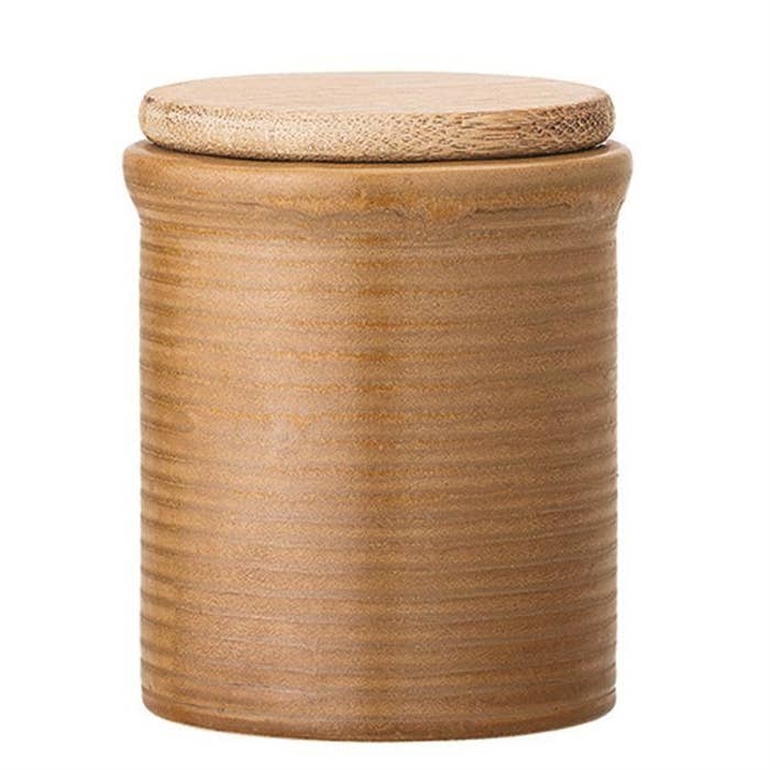 A cylindrical shaped canister with a ribbed siding and a wood lid