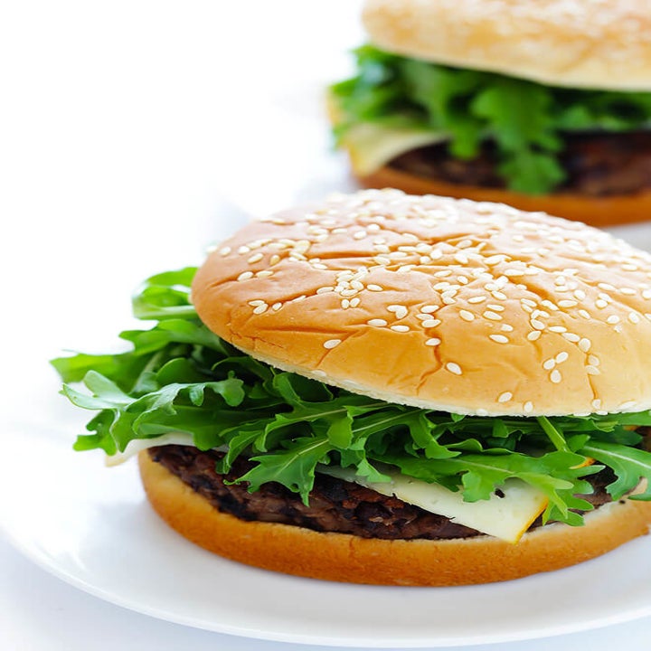 Two hamburger buns filled with black bean burgers, cheese, and arugula.