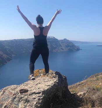 BuzzFeed editor Elizabeth Lilly in the full-length black leggings standing on a rock on a hike overlooking the ocean showing the back view
