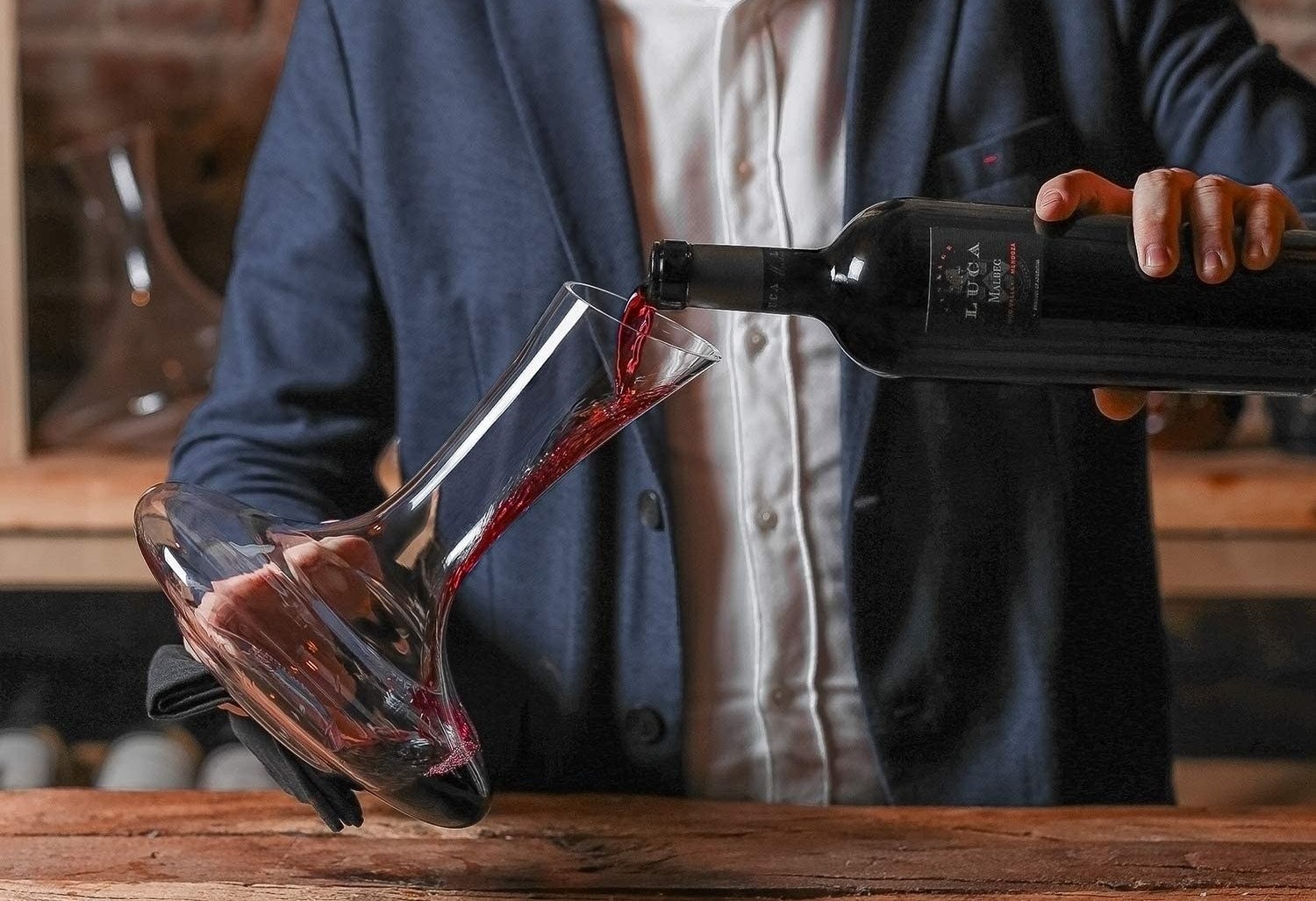 A person pours red wine into a decanter