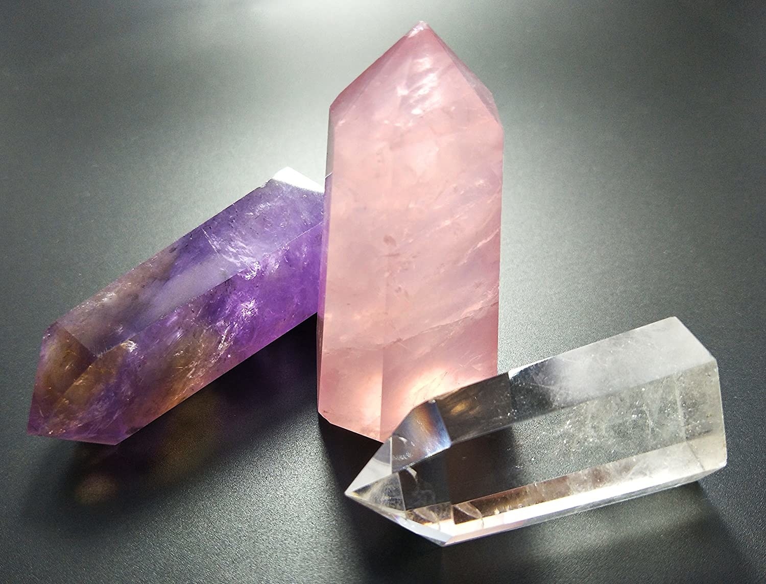 Two crystal points are flat on a table and one is upright