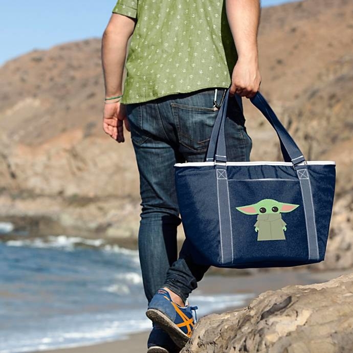 A model carrying the large navy tote with a cartoon Baby Yoda on it