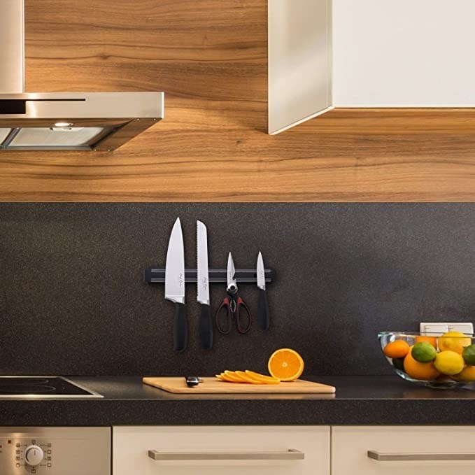 Kitchen knives and scissors standing on the wall with the help of the magnetic knife stand.