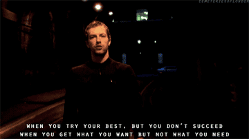 Gif of Chris Martin walking down a dark street with the lyrics when you try your best but you don&#x27;t succeed when you get what you want but no what you need on top