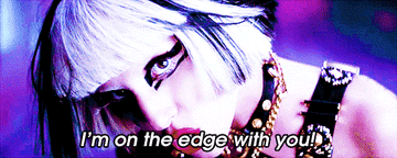 Gif showing Lady Gaga in the music video for Edge of Glory close up looking into camera with the lyrics I&#x27;m on the edge with you on top