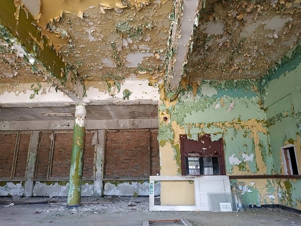 Old train station with decaying blue and green walls, paint chipping