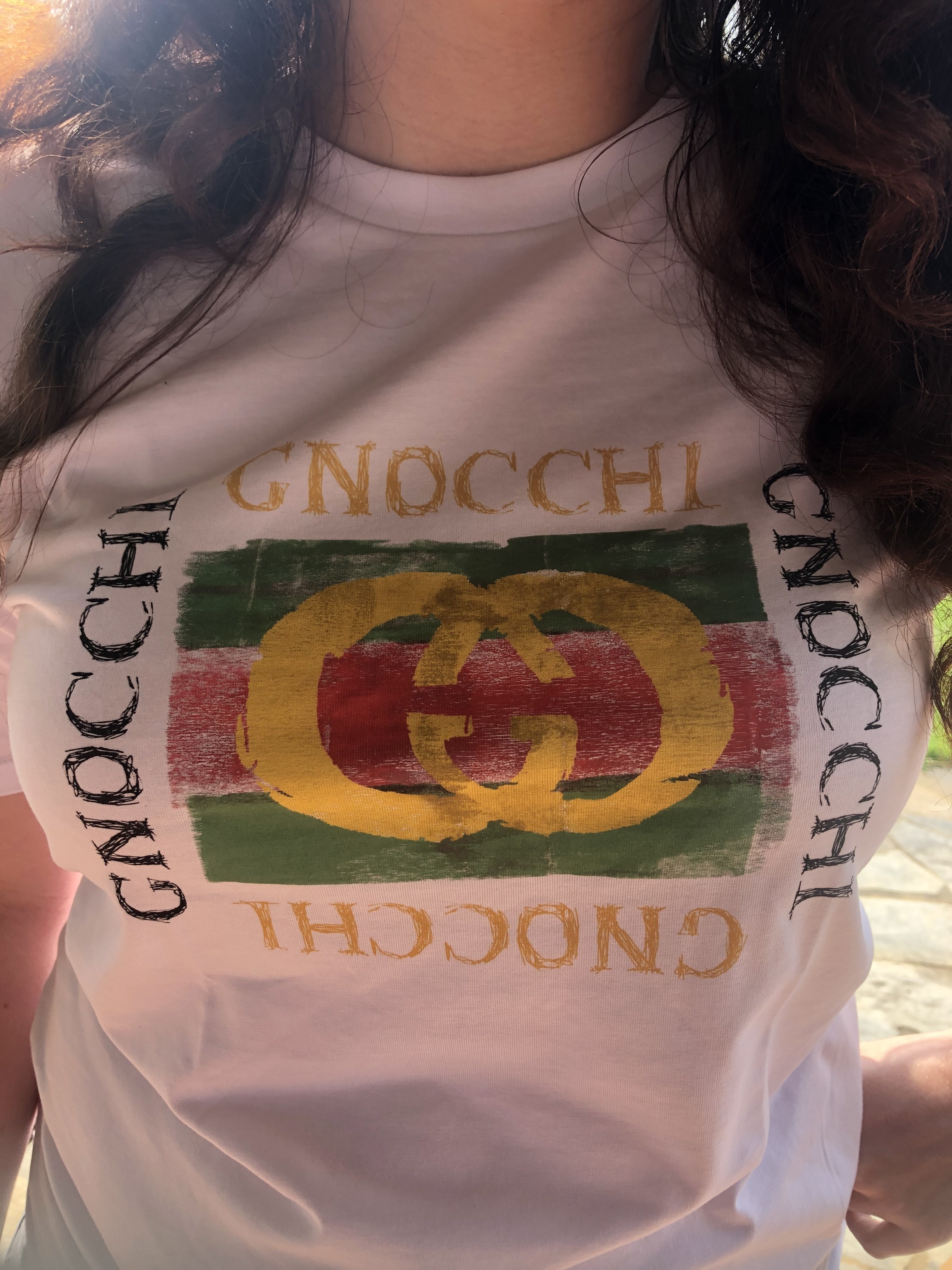 closeup of the print on the shirt of the writer wearing it. The print look like the double G Gucci logo except with the word &quot;Gnocchi&quot; instead of &quot;Gucci&quot;