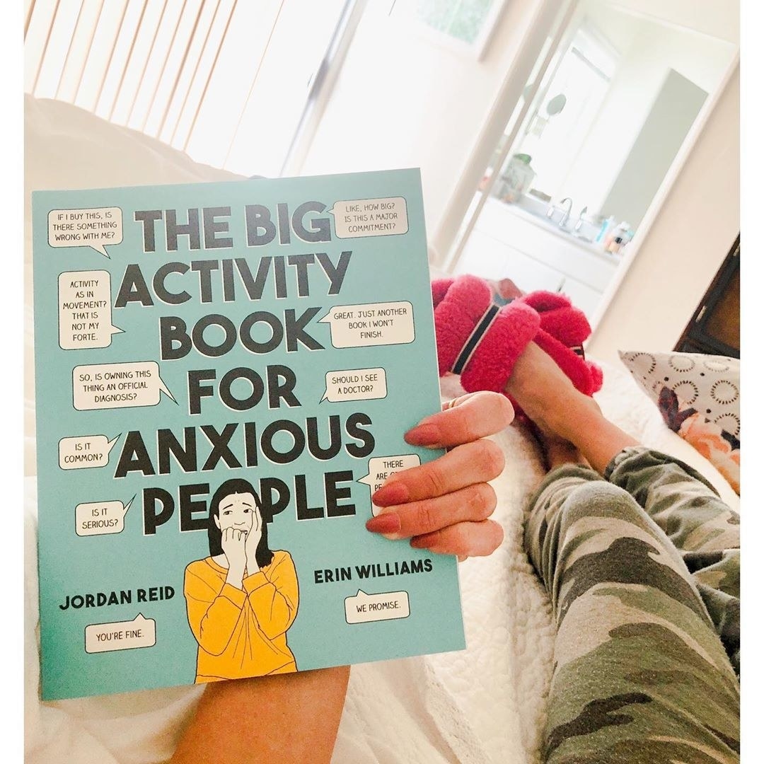 A book called the big activity book for anxious people being held in someones hand