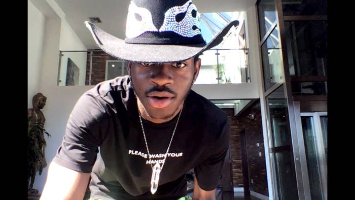 Lil Nas X wears a bedazzled cowboy hat with a dark t-shirt that reads &quot;please wash your hands&quot;