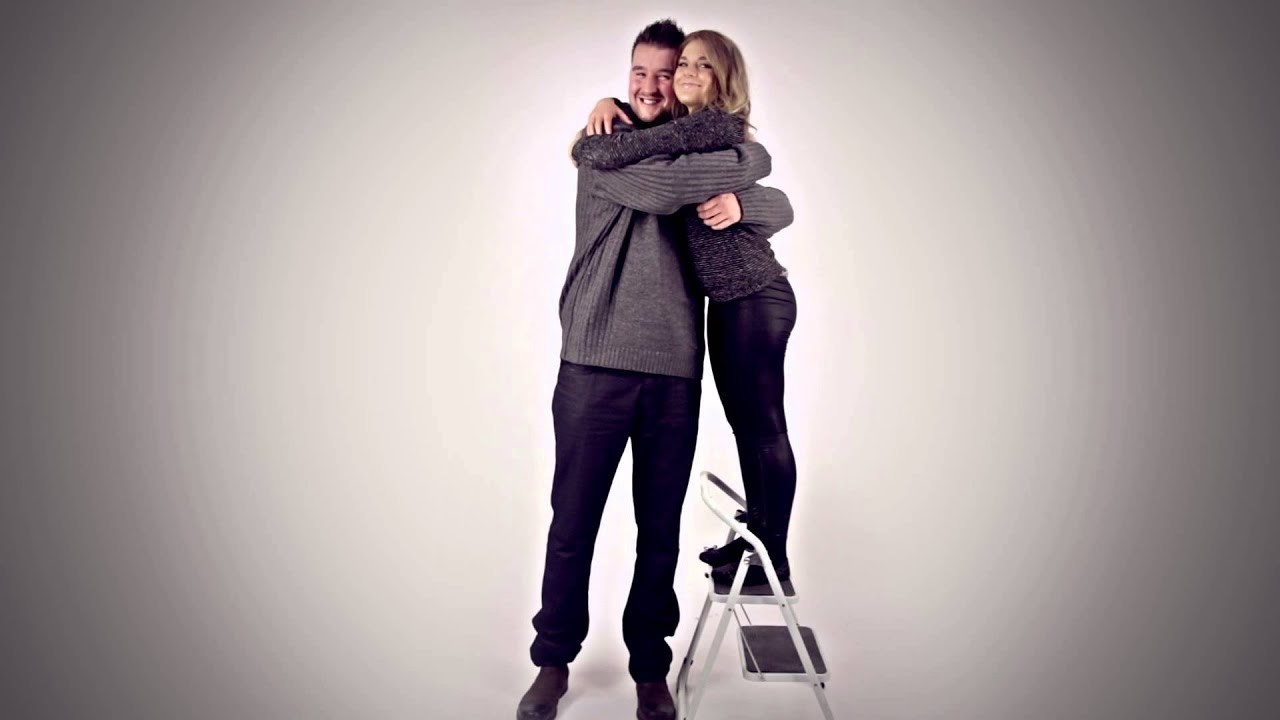 A short woman on a stepping stool hugging a tall man