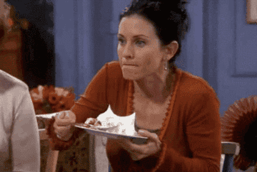 Monica from &quot;Friends&quot; holding a plate and happily rubbing her stomach after a good meal.