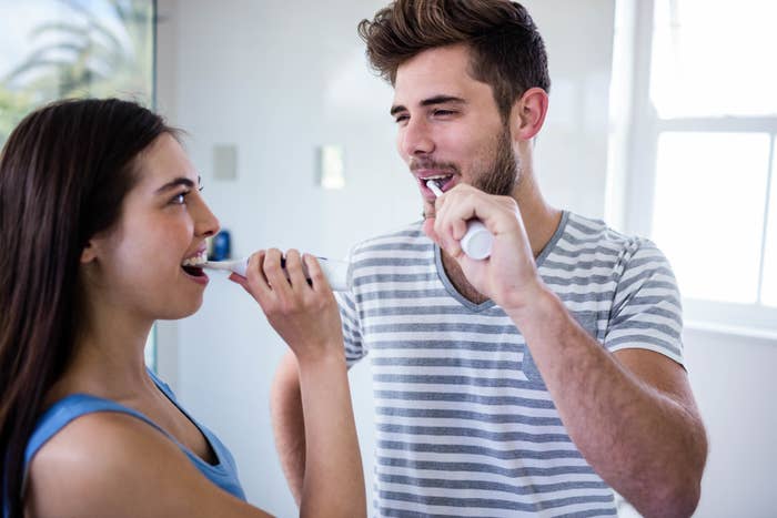 Couple brushing their teeth together and smiling