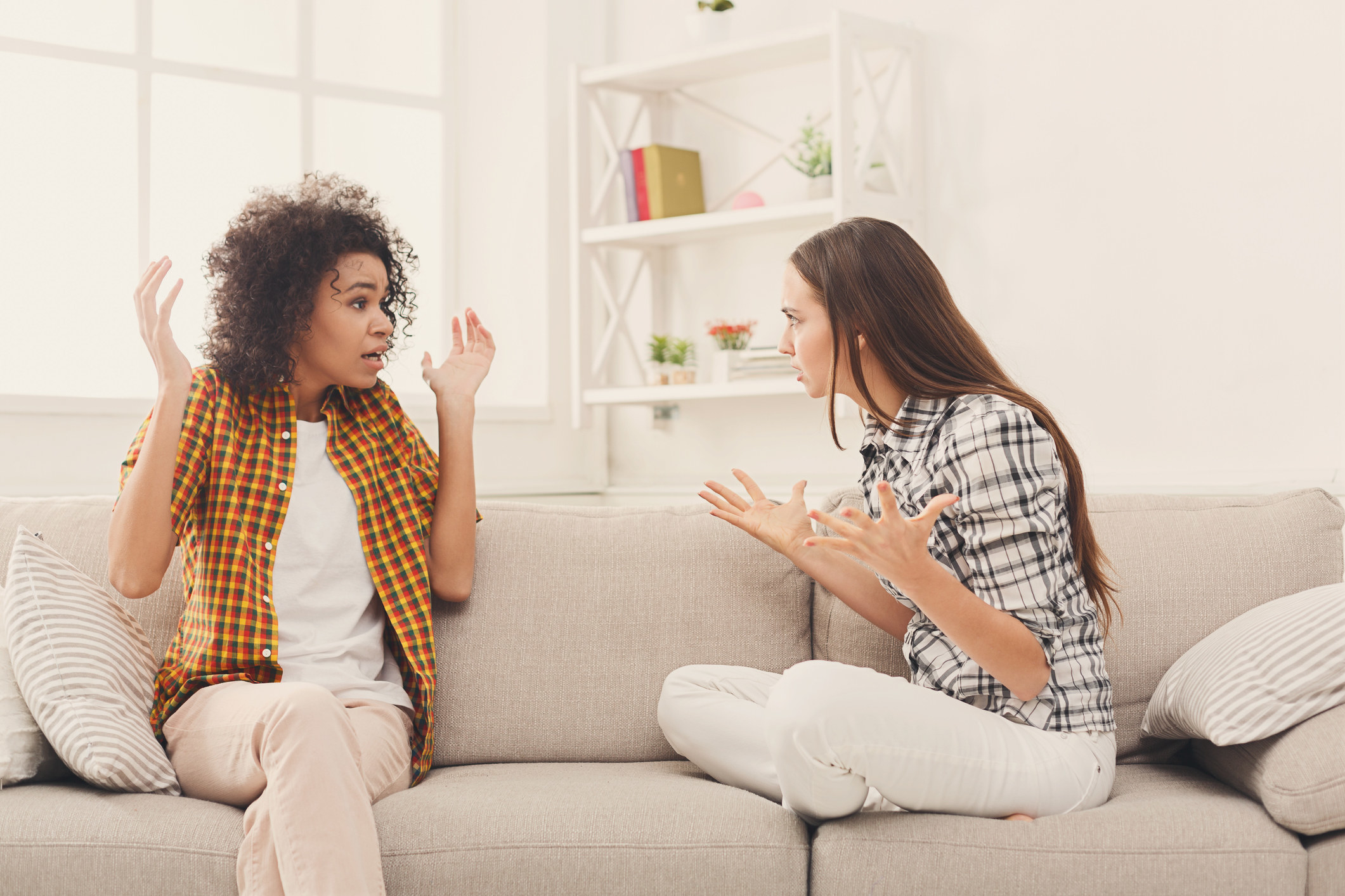 Two women on a couch having a tense argument