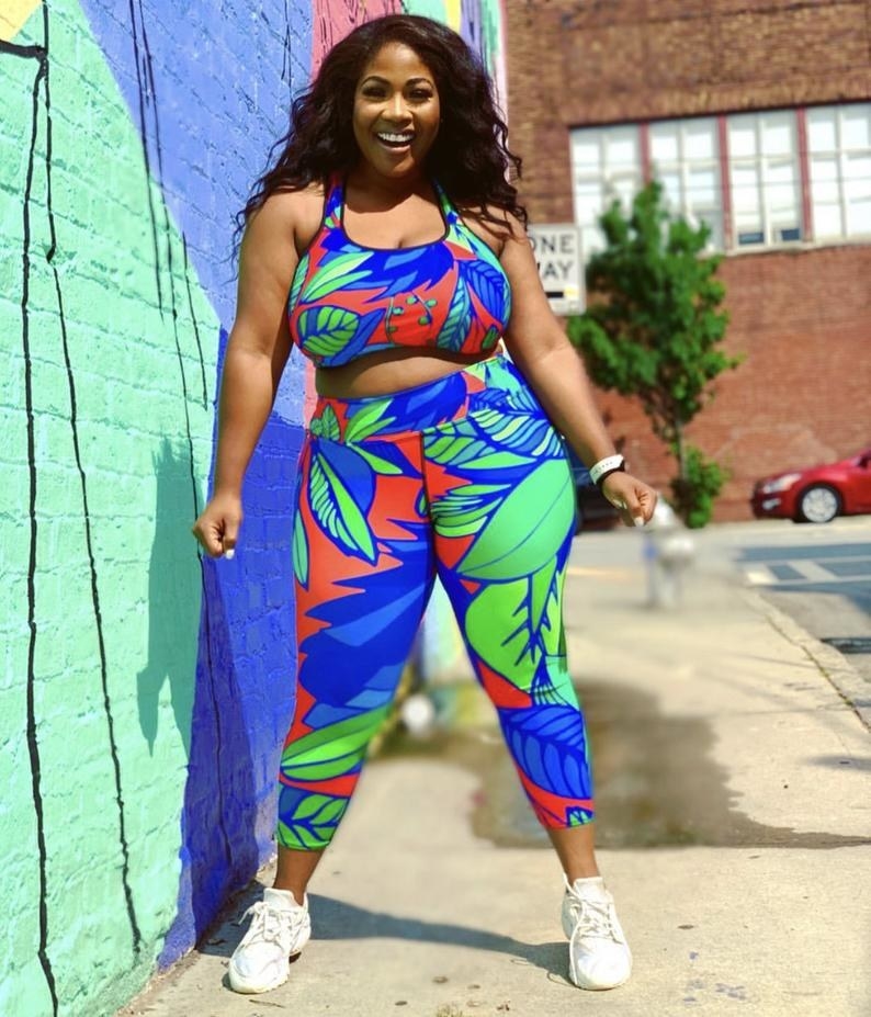 model wearing the bright floral sports bra and matching leggings in green, blue, and red