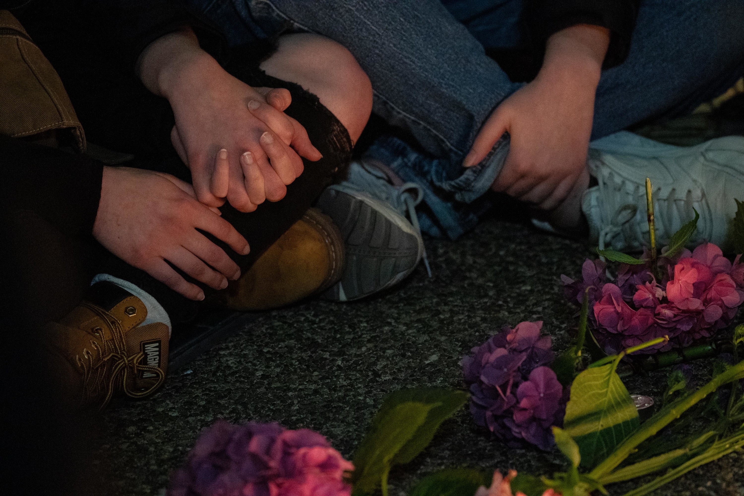 People sitting on the ground hold hands in front of flowers