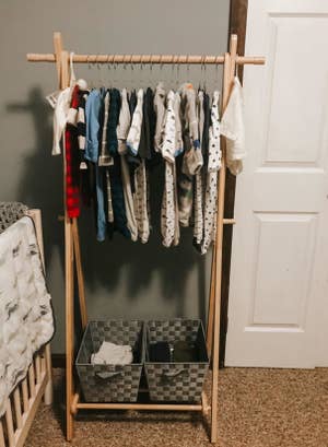 reviewer photo of a front view of the rack, with baby clothes hung up and boxes 