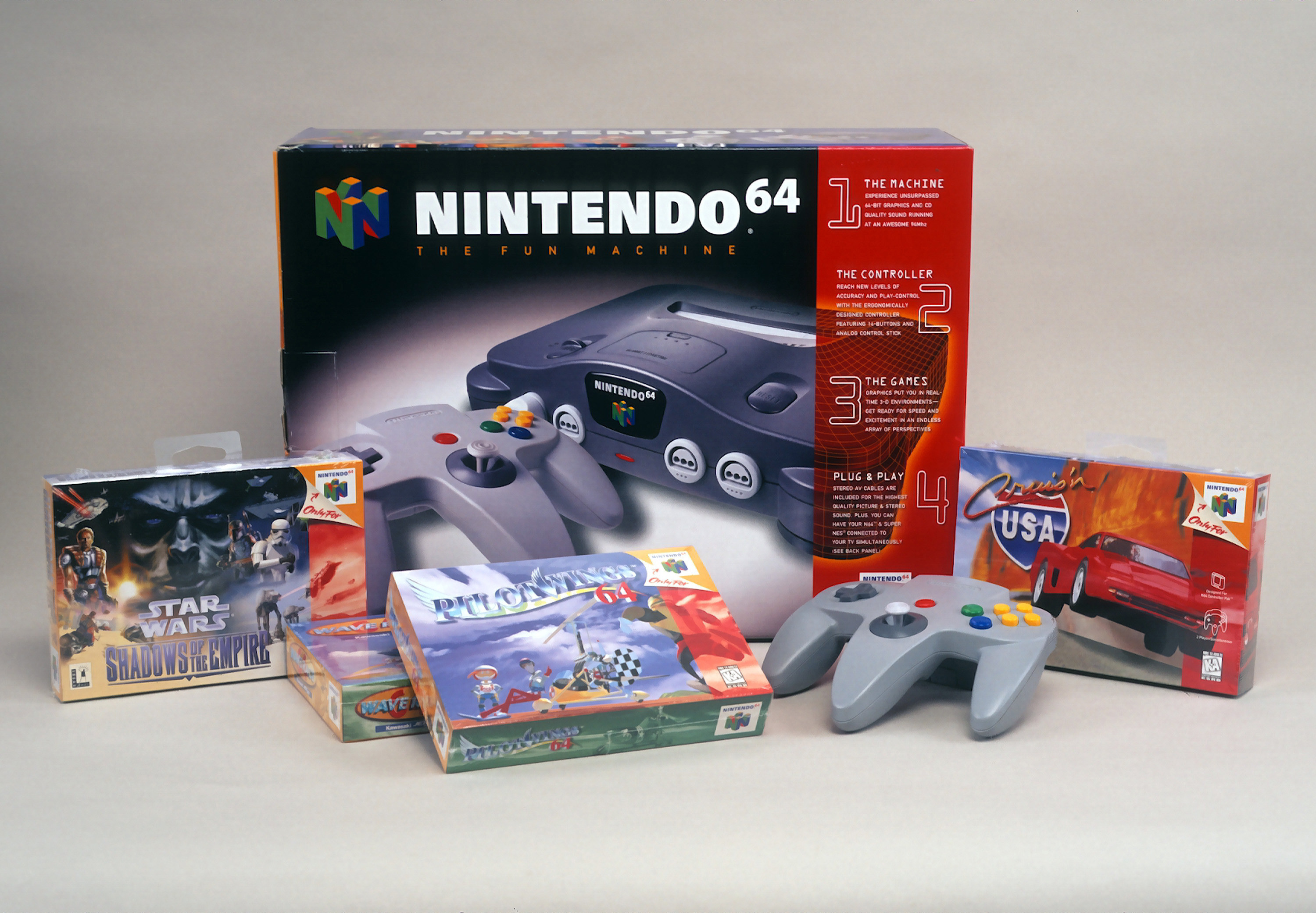 A product shot of a Nintendo 64 box alongside a controller for it and four different games