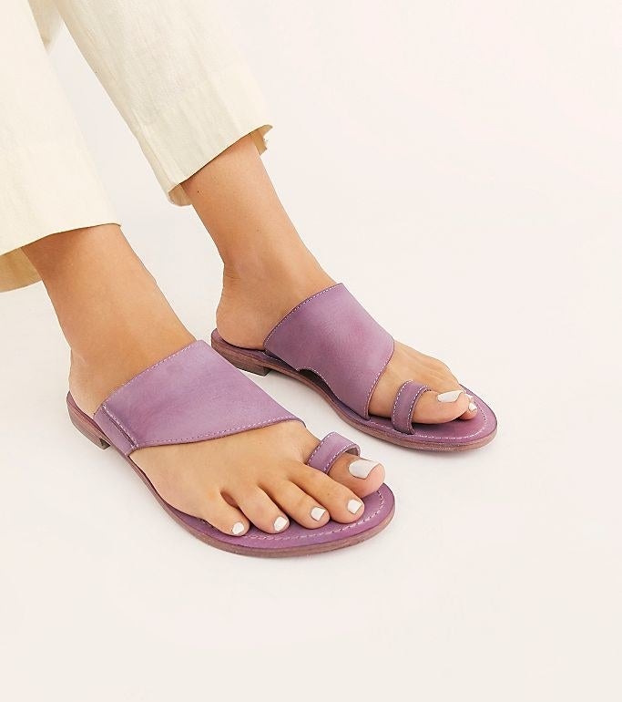 model&#x27;s feet with light purple leather sandals with strap across foot and a toe loop