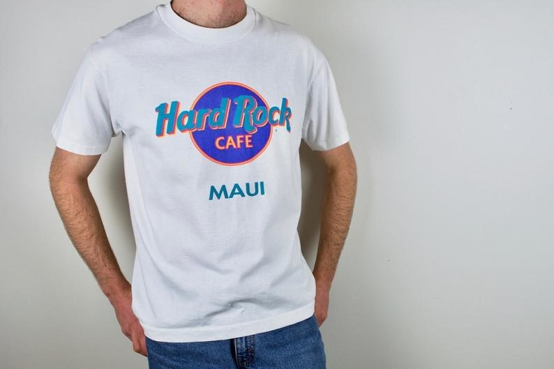 照片中的男子穿着90年代白色硬石咖啡馆:毛伊岛t恤，上面有蓝绿色和紫色的字母。
