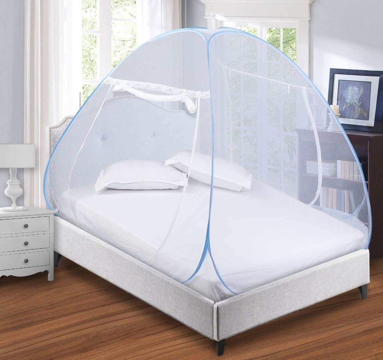 A white and blue mosquito net tented over a single bed.