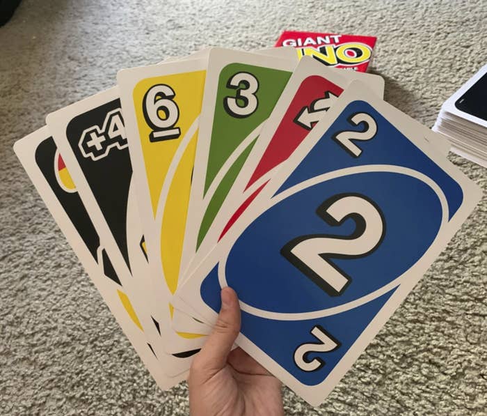 reviewer&#x27;s hand holding a hand of the giant uno cards — they&#x27;re bigger than the reviewer&#x27;s hand