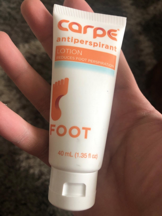 An open hand shows the Carpe anit-perspirant foot lotion in a tube