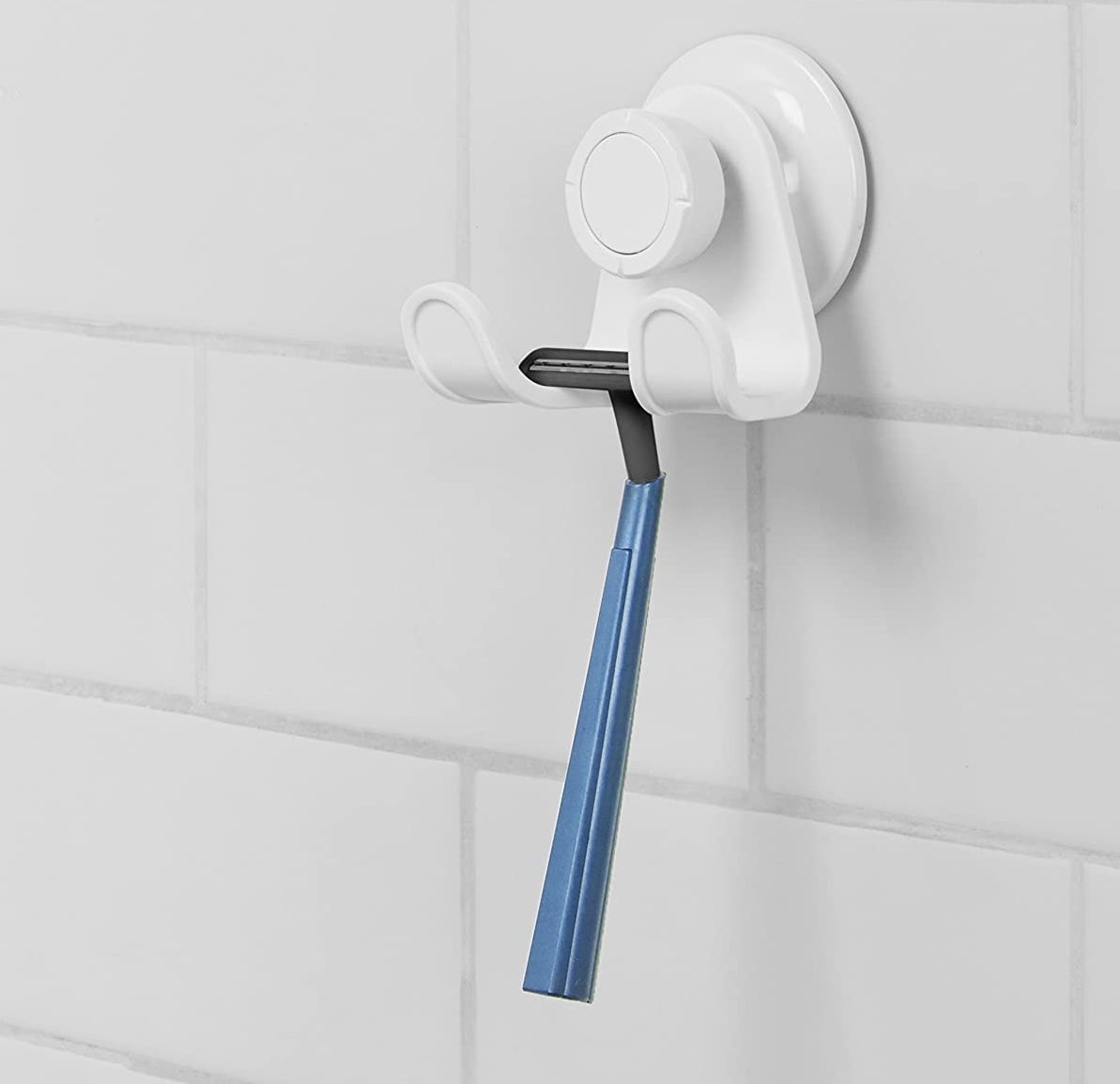 A razor hanging from a small hook on a bathroom wall