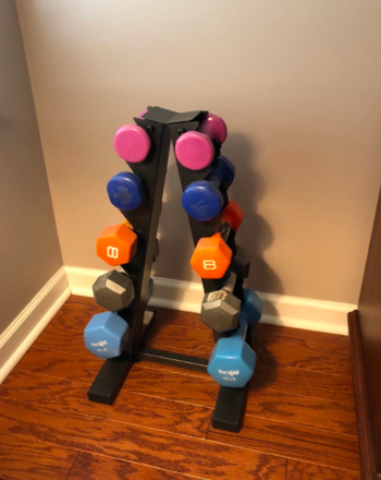Reviewer's black dumbbell storage rack with pink, yellow, and blue weights