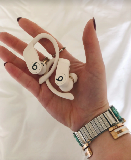 BuzzFeed Editor Emma McAnaw holding a pair of white Powerbeats headphones in her hand