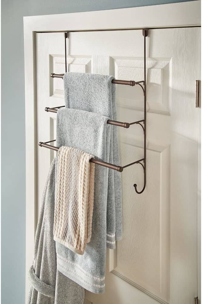 A multi-tiered shelf hanging over the bathroom door with towels and a bathroom hanging from the shelves