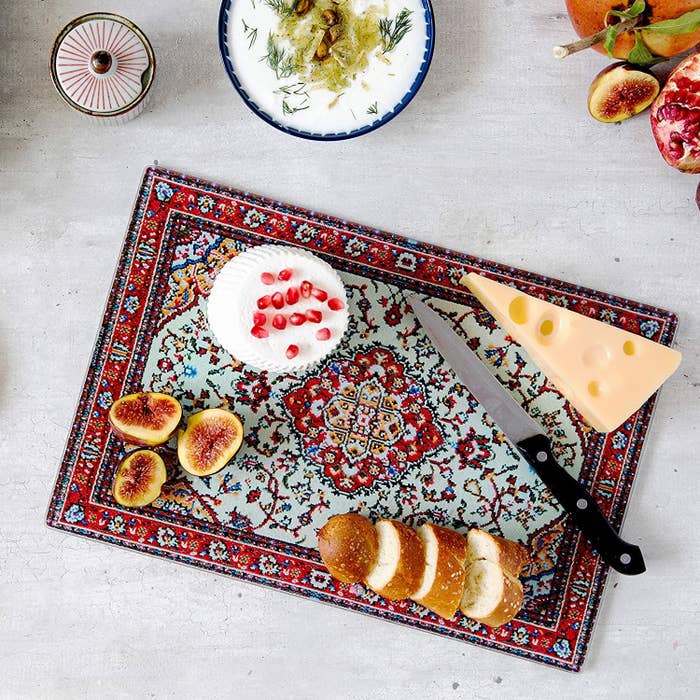 the red and blue cutting board with cheese and figs on it 