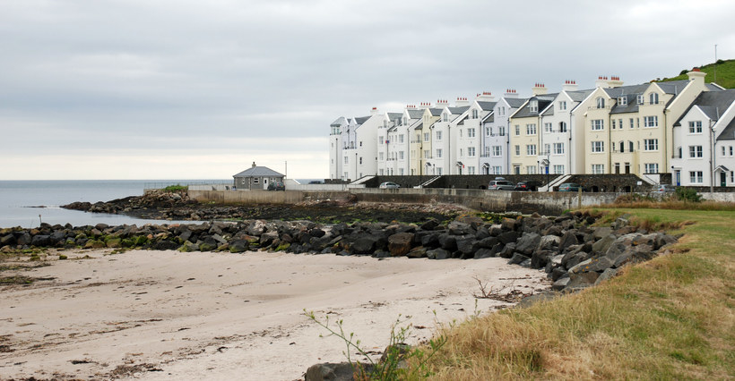 A view across a beach towards the coast road in Cushendun, Northern Ireland on a grey day