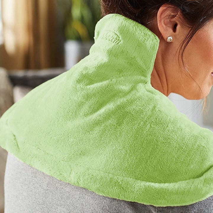 A shot from behind of a person wearing the heat pad over their shoulders