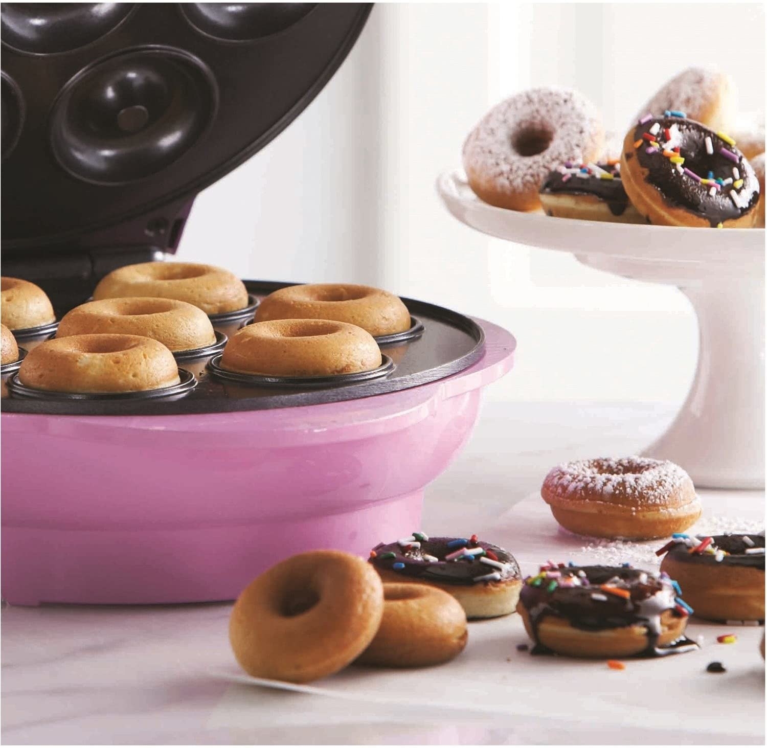 A close up of the inside of the donut maker where fresh mini donuts are visible