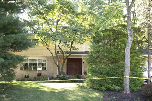 The two-story home of the judge is pictured with police tape strung between trees and bushes surrounding the property.