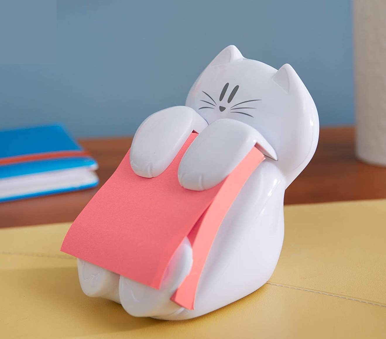 The post it holder is sitting on a desk with a whole pad of post its on it