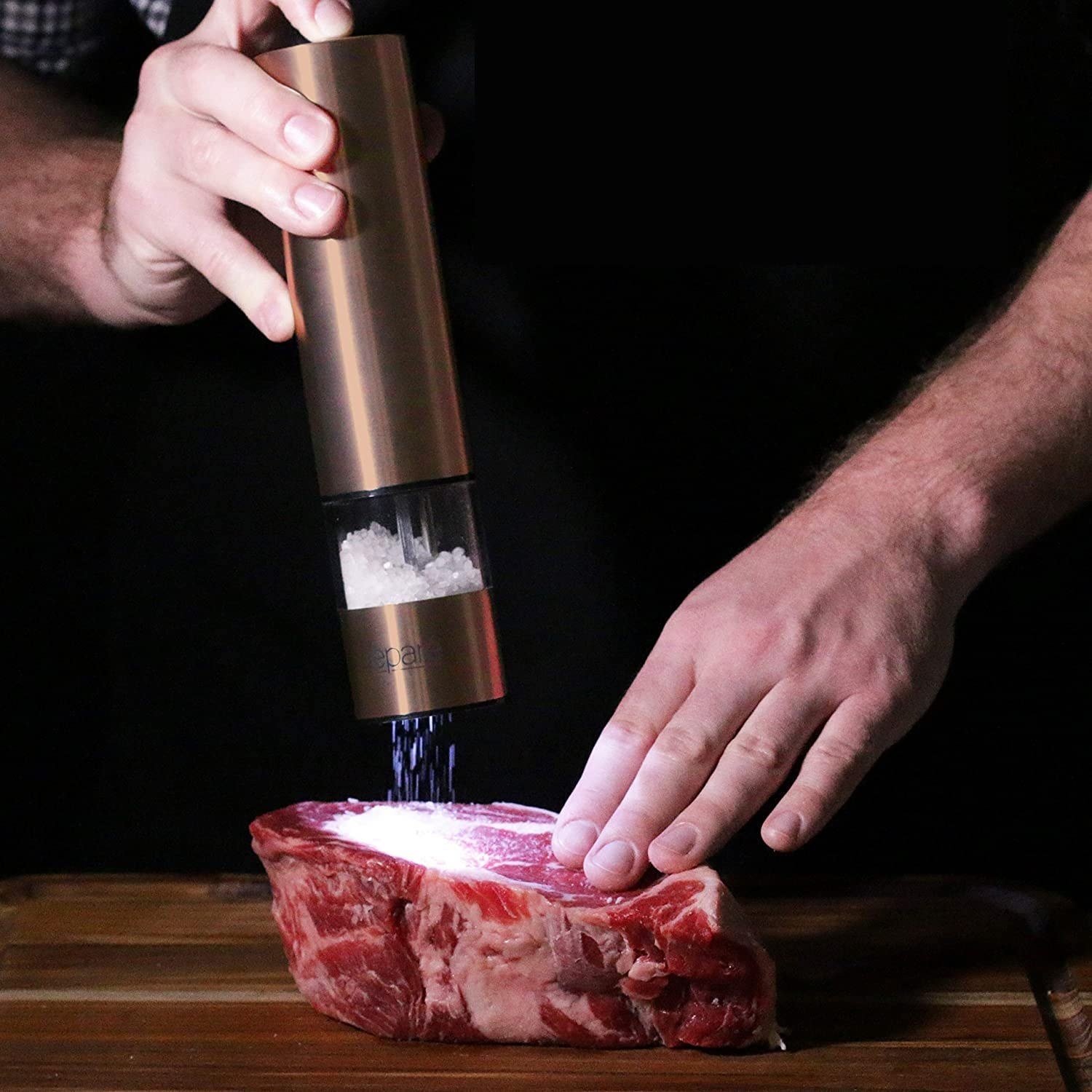 A person grinds salt onto a thick slab of steak