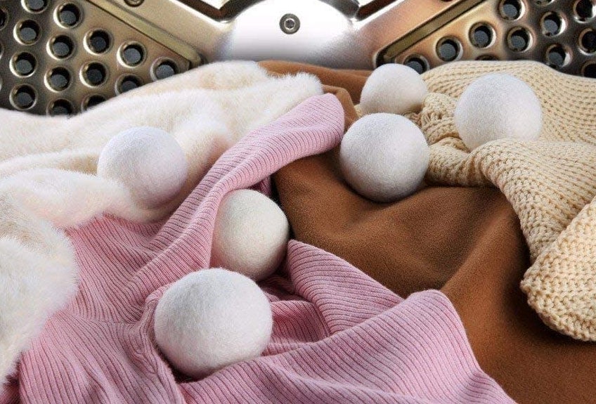 Six fuzzy wool balls in a dryer with a load of laundry