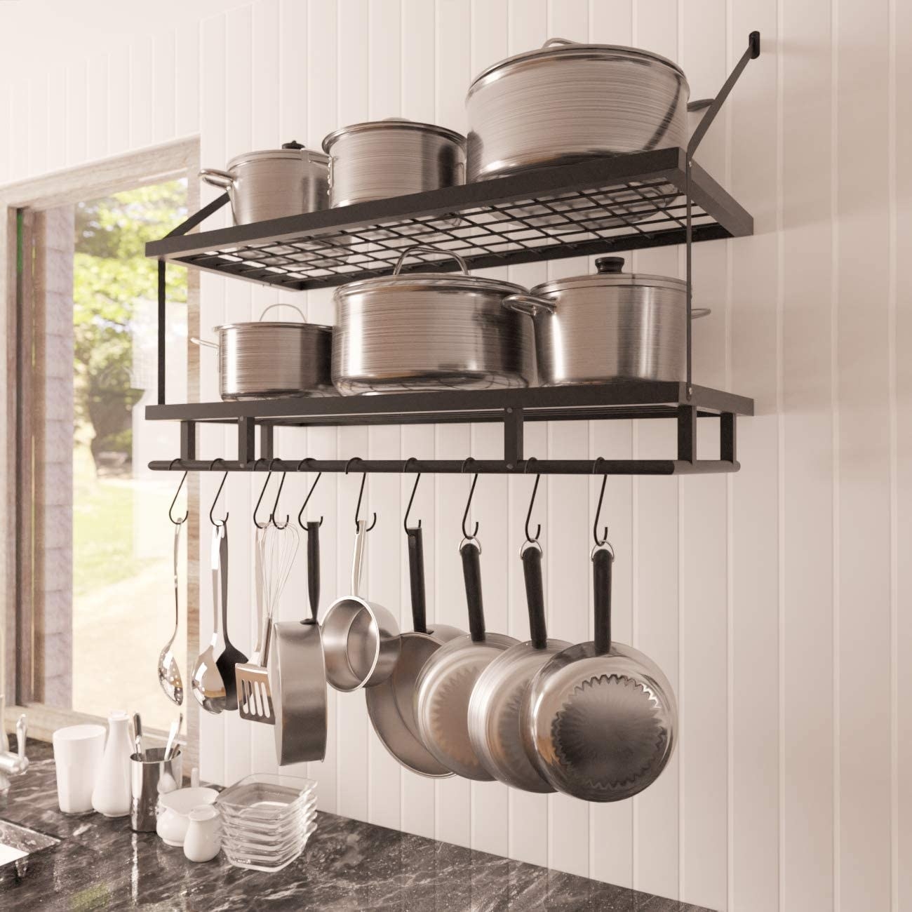 A metal shelf on a wall. with shelves for pots and hooks with pans hanging off of it