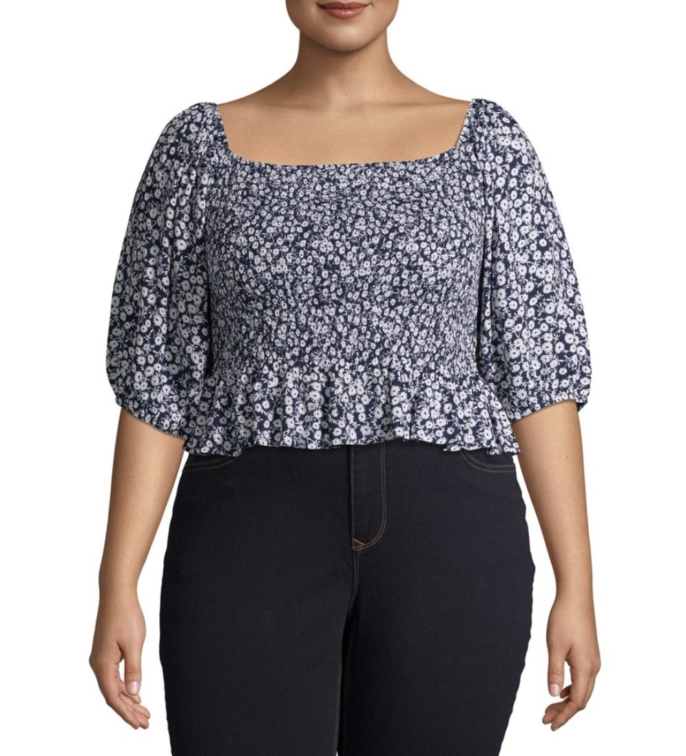 A model in a puff sleeve square cut ruffled blue blouse with floral designs 