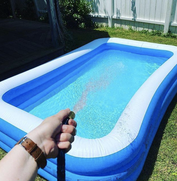 a reviewer filling the rectangular blue pool with a hose