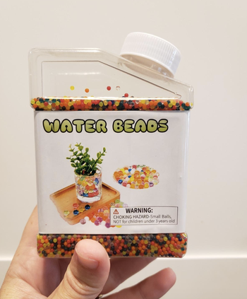 A reviewer holding up a small container of tiny tiny beads 
