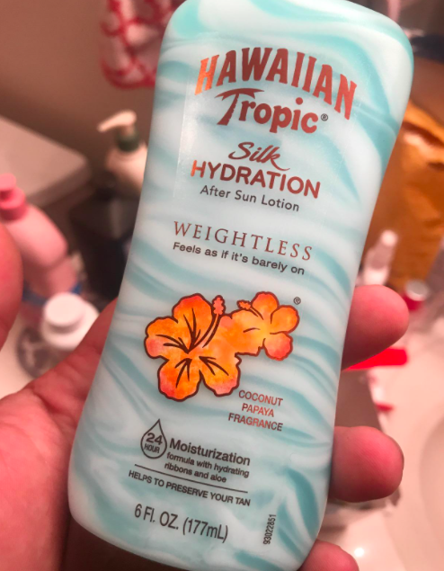 A reviewer holding a bottle of the Hawaiian Tropic after sun lotion