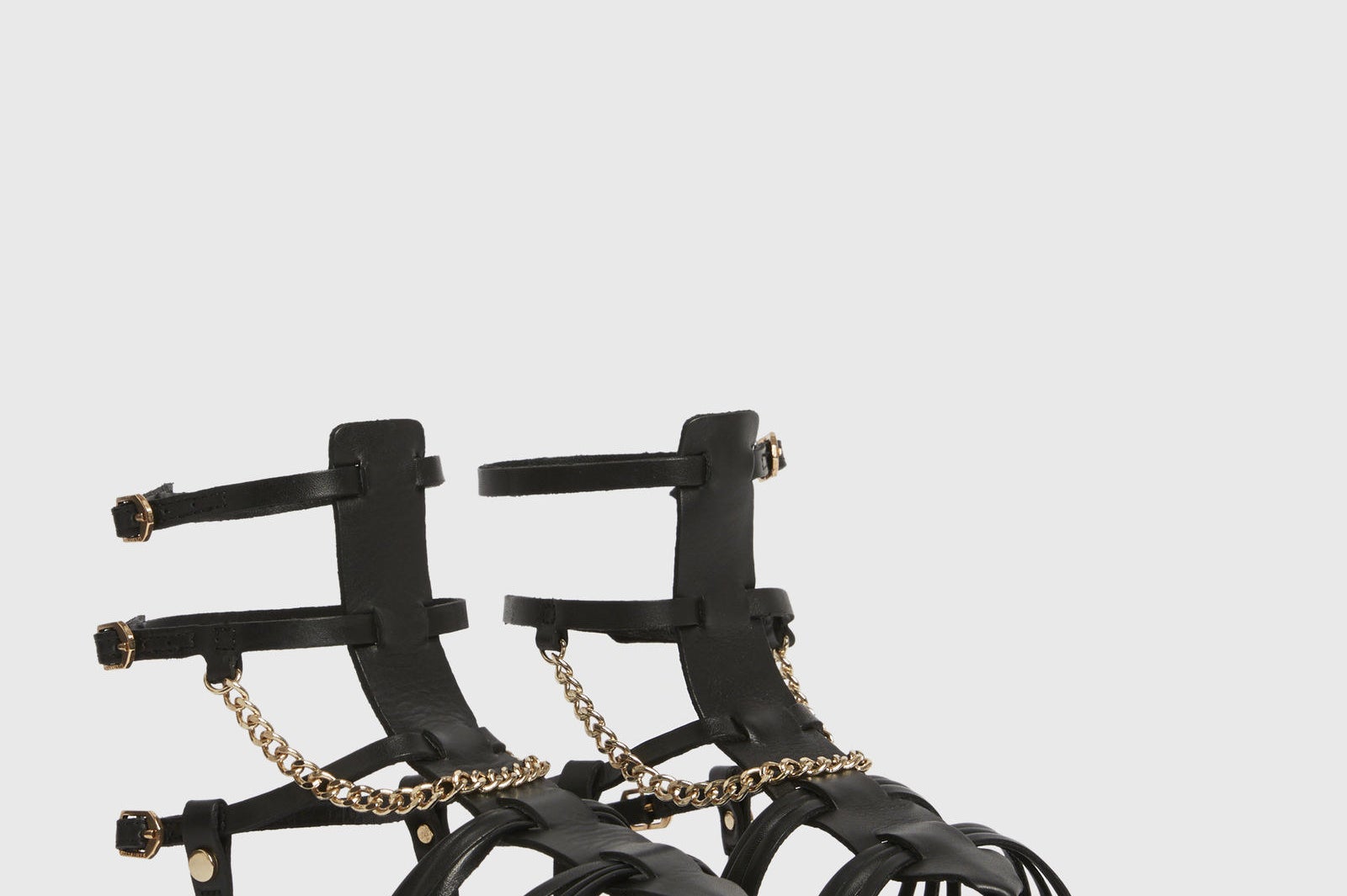 black gladiator style sandals with a gold tone chain as an accent and two straps that go right at the ankles