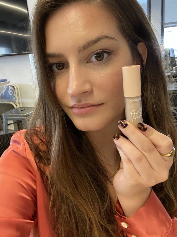 BuzzFeed Shopping writer holding the concealer bottle close to her face showing how she doesn&#x27;t have undereye bags